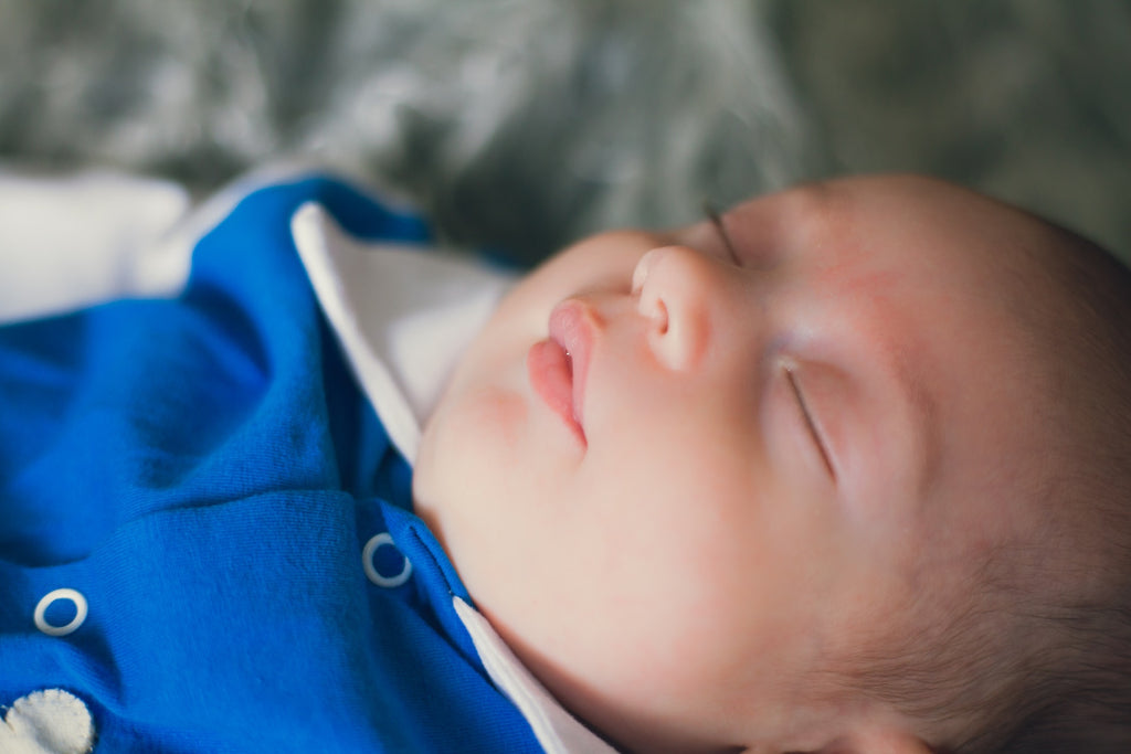 Sleeping baby in a blue sleepsuit