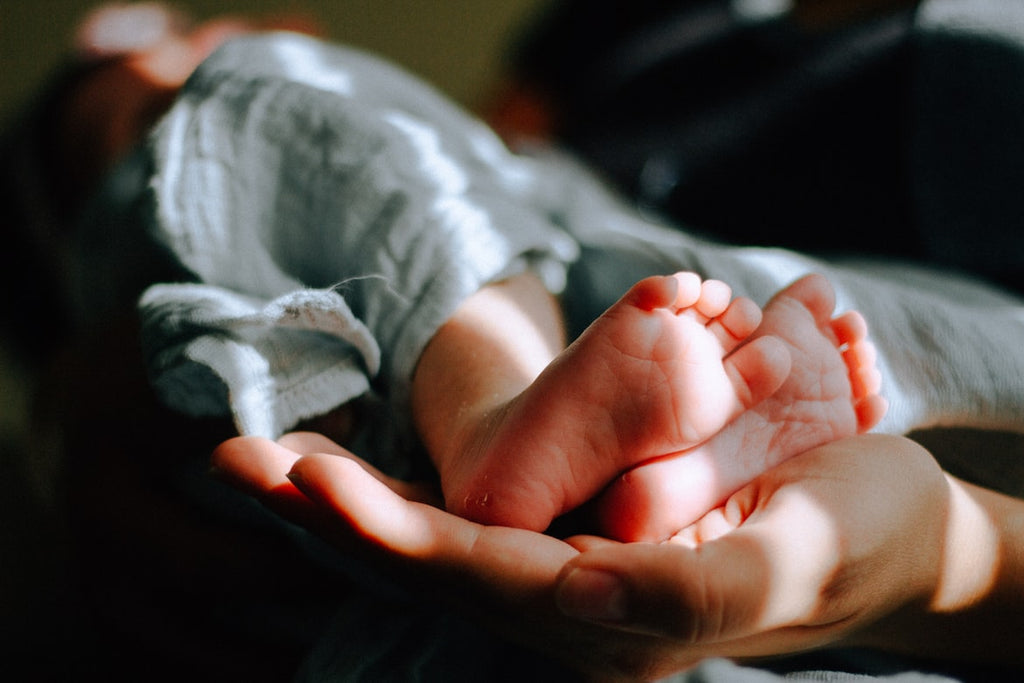 Woman's hands cradling newborn feet