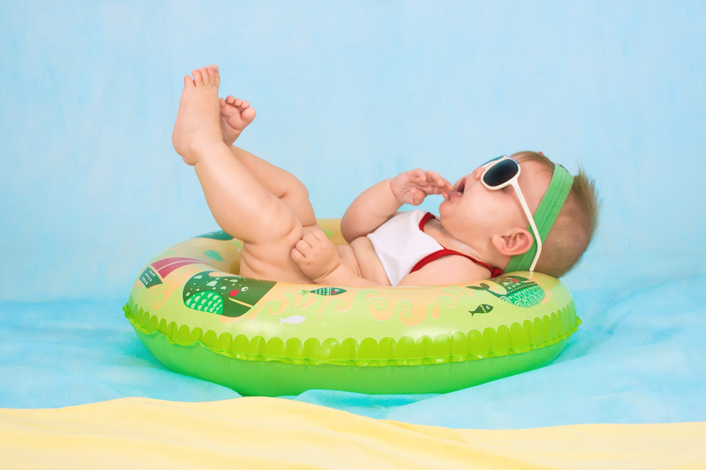 Baby lying in an inflatable rubber ring with sunglasses on